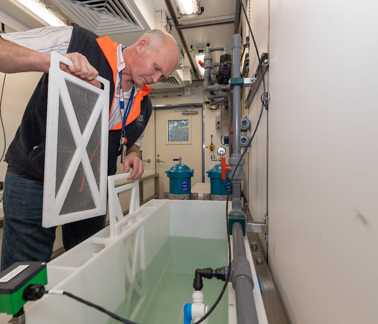 Scientist leaning over a tank of water.