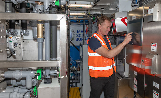 Man standing at a control panel in a mechanical plant room.