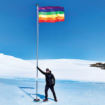 Station Leader Matt Williams leading against a flag pole flying the Pride flag.