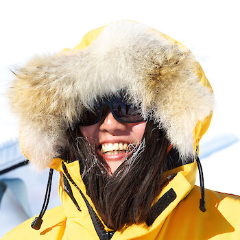 Expeditioner wearing yellow Antarctic clothing and sunglasses at the Aurora Basin North campsite.