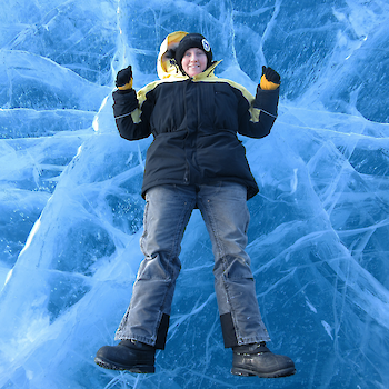 Looking down on expeditioner lying on frozen fresh water lake.