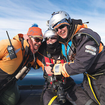 Three whale scientists in boat pose for photo.