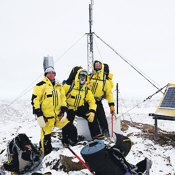 Group of three expeditioners standing near VHF repeater.