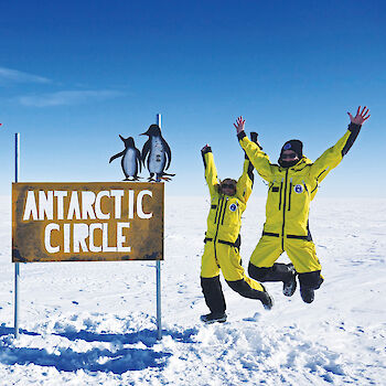 Group of researchers jumping at Antarctic Circle sign.