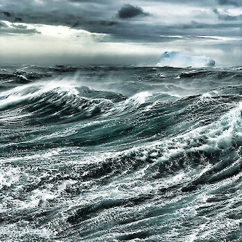 Atmospheric image of the swirling waves of the Southern Ocean from a ship with gathering storm clouds above.
