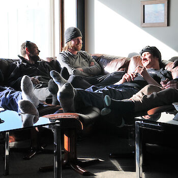 Group of expedioners lounging on couches inside.