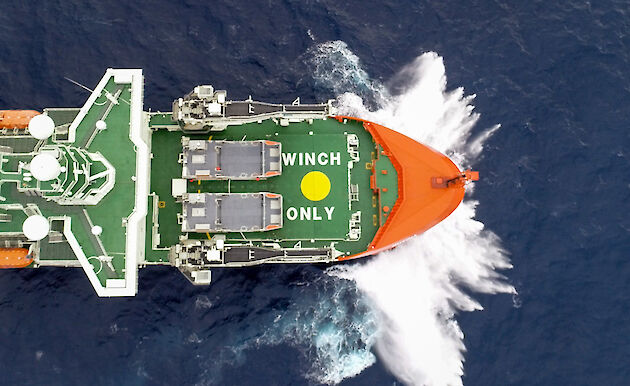 An aerial shot looking down on to the bow of a moving ship