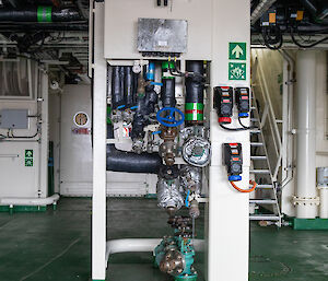 An array of valves and pipes connect shipping containers to the ship's services.