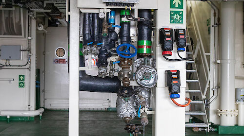 An array of valves and pipes connect shipping containers to the ship's services.