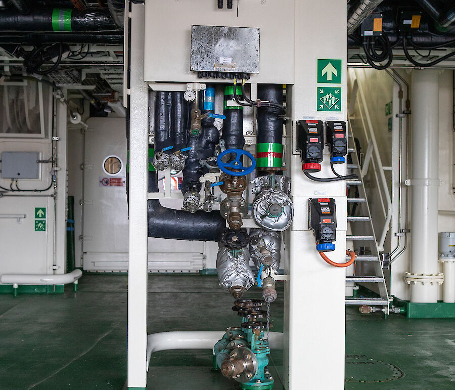 An array of valves and pipes connect shipping containers to the ship's services.