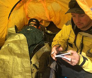 A person lies in a yellow tent as part of a Search and Rescue training exercise
