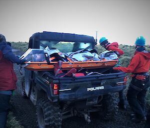 A stretcher with a patient is being loaded on the back of a small vehicle as part of a Search and Rescue exercise