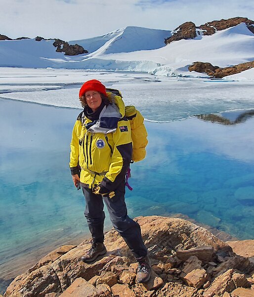A woman in cold weather gear standing in front of a beautiful blue icy lake