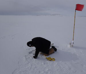 A man checking the 'freeboard' in the hole - the difference between the water level and the top of the ice