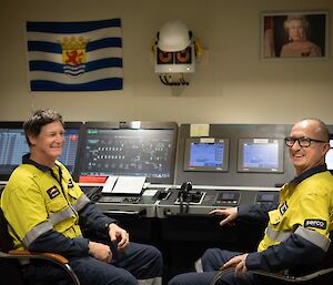 Two men sit at the controls in the engine room