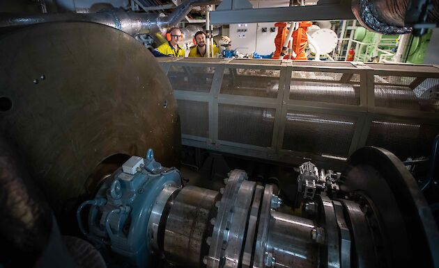 The flywheel of the ship's engine being checked by two workers