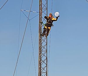 A person half way up an aerial "holds" the moon in their hands for photographic effect