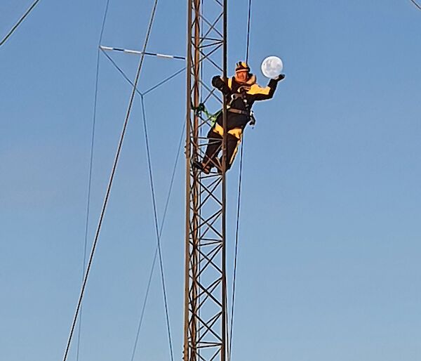 A person half way up an aerial "holds" the moon in their hands for photographic effect