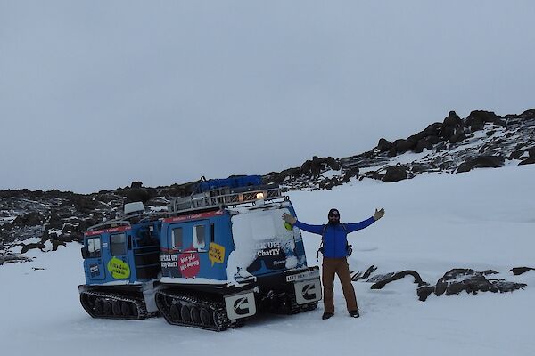 A man and a Hagg parked on a rocky and snowy hill