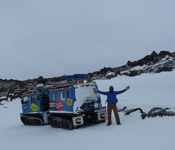 A man and a Hagg parked on a rocky and snowy hill