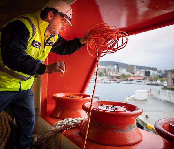 Crew about to throw a rope from the ship to the wharf.