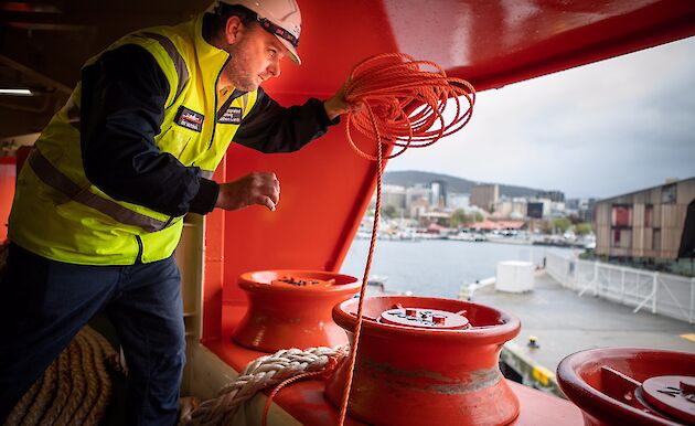 Crew about to throw a rope from the ship to the wharf.