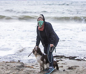 Woman with dog on the beach; RSV Nuyina in the background