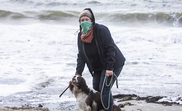 Woman with dog on the beach; RSV Nuyina in the background