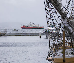 RSV Nuyina in the background framed by sailing ship in the foreground.