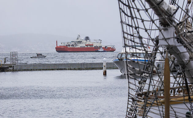 RSV Nuyina in the background framed by sailing ship in the foreground.