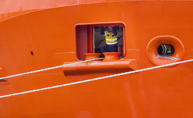 Crew member looking out from the RSV Nuyina, near where ropes are tied to the ship