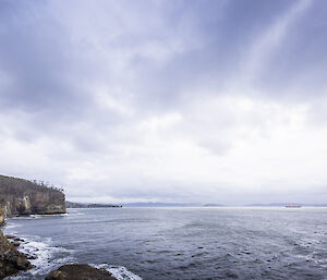 Cliffs and dramatic sky, with Nuyina small in the background