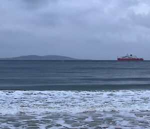 Red ship sailing on river on cloudy on overcast day