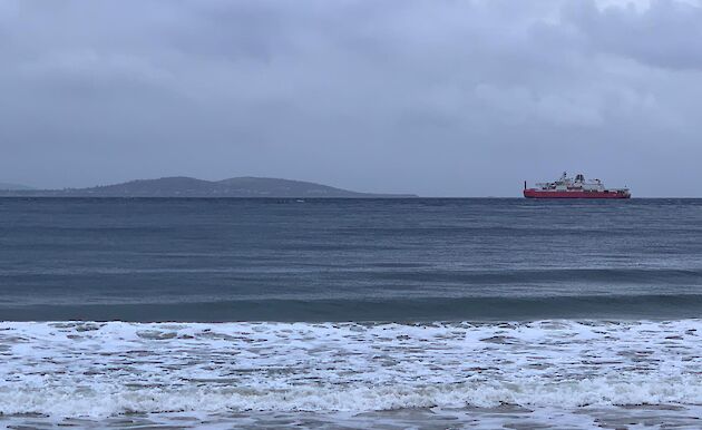 Red ship sailing on river on cloudy on overcast day