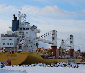 Large yellow and white cargo ship sitting in a snow covered dock