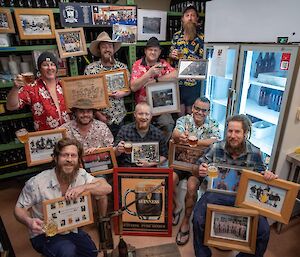 A group of people in Hawaiian shirts holding memorabilia and a glass of beer each
