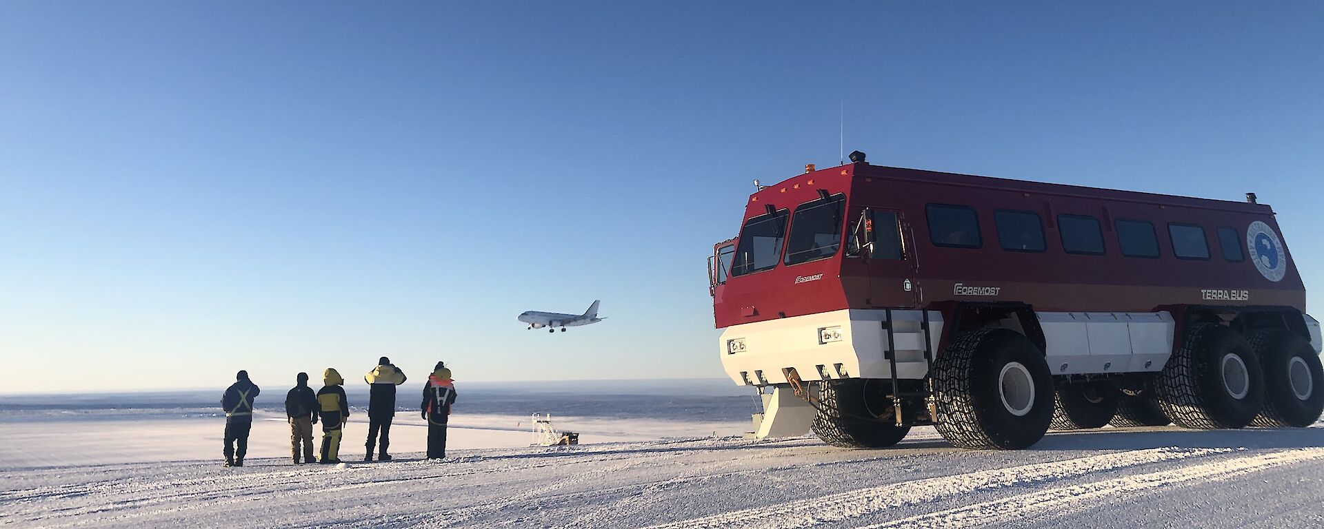 Group of expeditioners near bus, with an aeroplane in the background