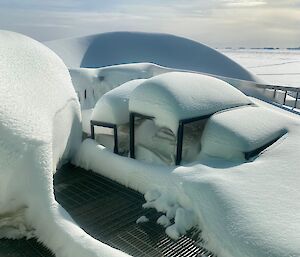 A picnic table on a metal deck with deep snow on all the flat surfaces