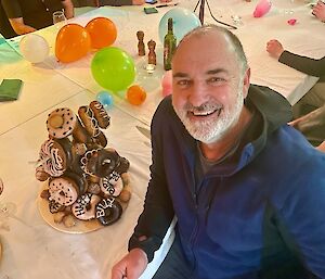 Birthday cake of colourful donuts stacked high around a timber frame.