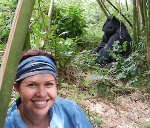 A woman in a forest with a gorilla behind her