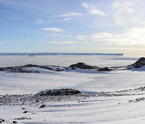 A panorama of the bay at Casey showing a summer day with blue sky and white ice and snow.