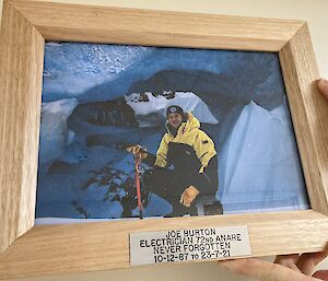 A picture of Joe in a handmade timber picture frame with plaque that reads “Joe Burton, Electrician 72nd ANARE, Never forgotten, 10-12-87 to 23-7-21”.