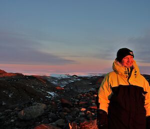 A man named Joe standing in the rocky hills at Davis illuminated by the sun set.