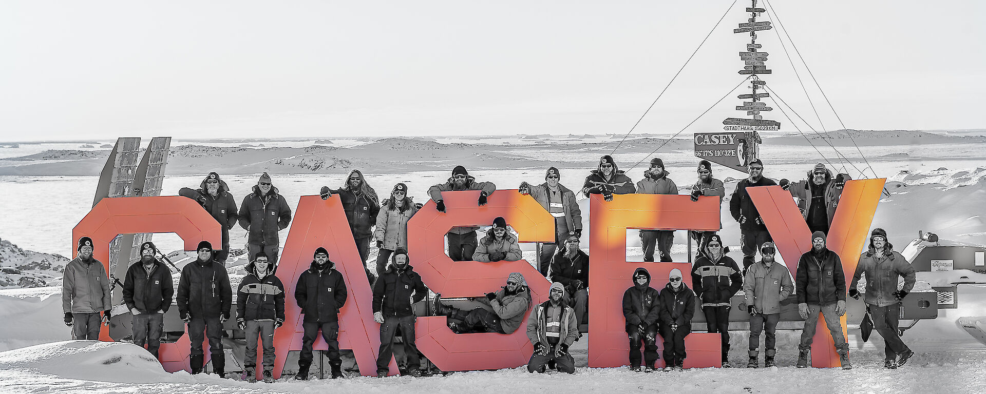 A team of people surround the large red Casey sign