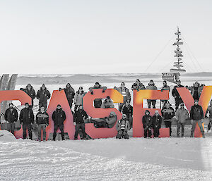 A team of people surround the large red Casey sign