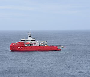 A large red icebreaker sits in the grey ocean