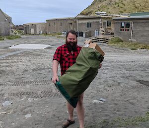 A bearded man carries a bag full of newly arrived mail