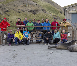 A group of expeditioners stand in from of the gate with Macquarie Island written on it.