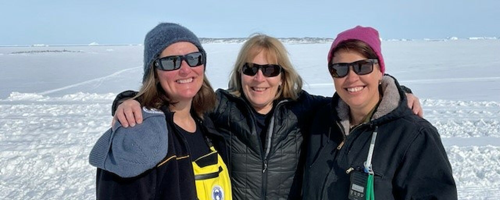 Three woman in sunglasses standing in the snow