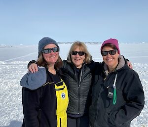 Three woman in sunglasses standing in the snow